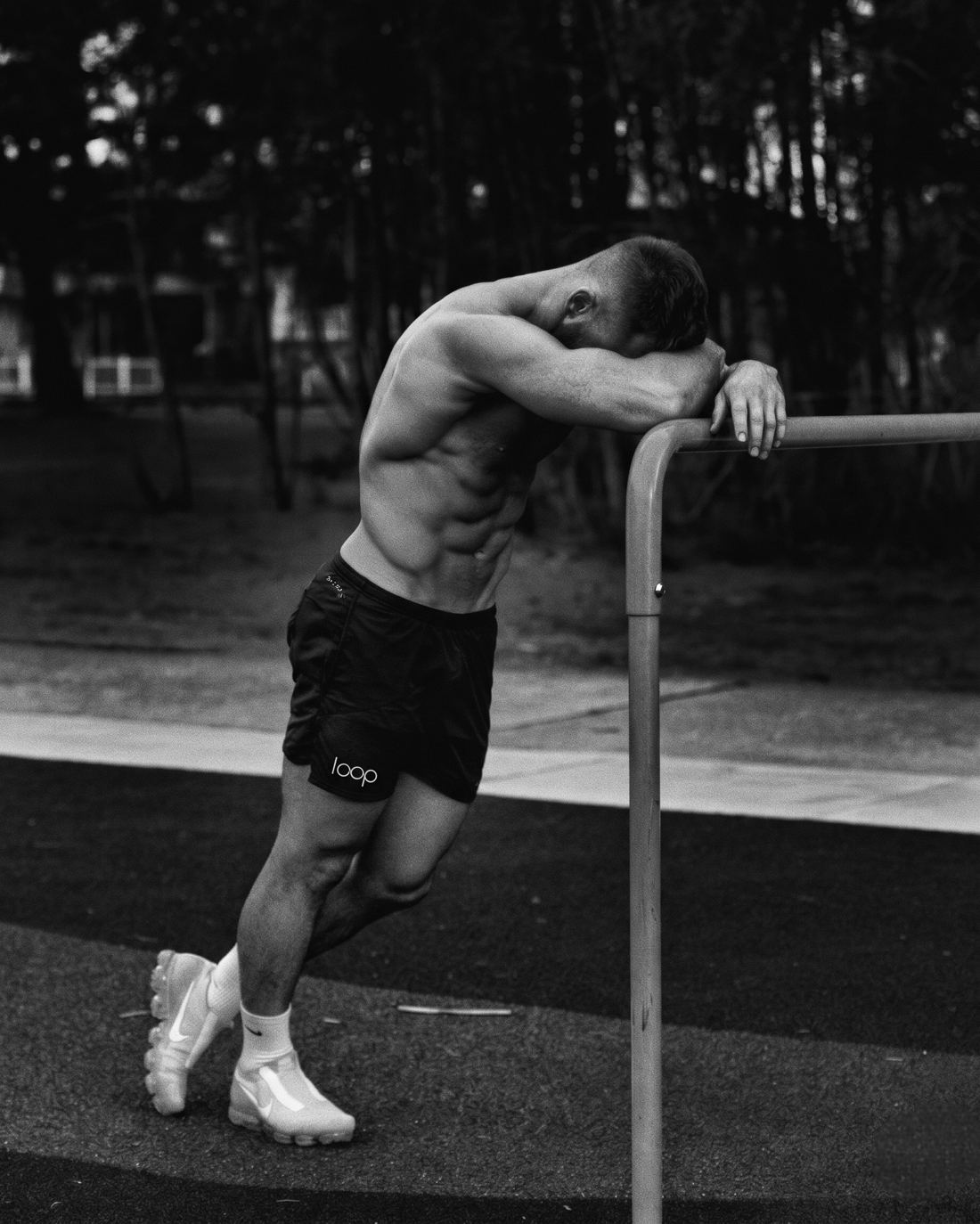 Athlete resting on a pull-up bar in black Loop shorts