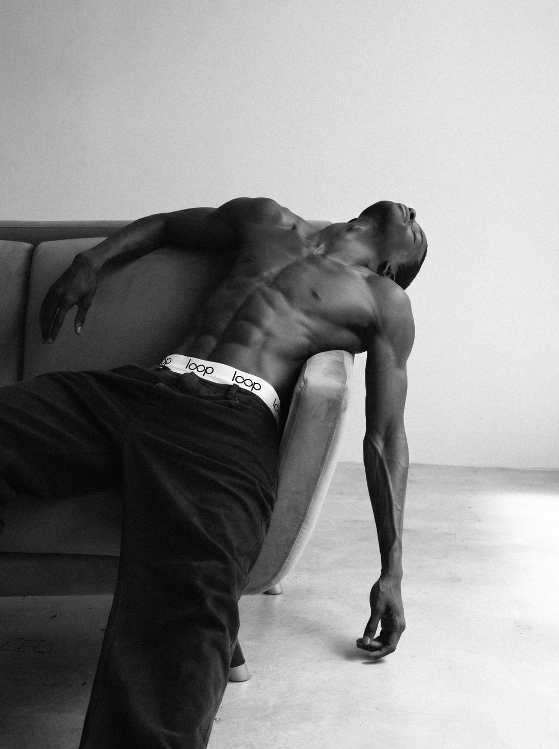 Athlete reclining on a sofa in black trousers with a Loop waistband
