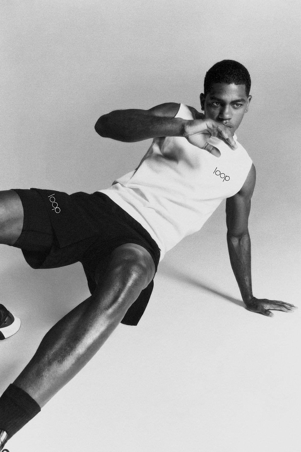 Athlete in a white Loop tank and black shorts posing on the floor