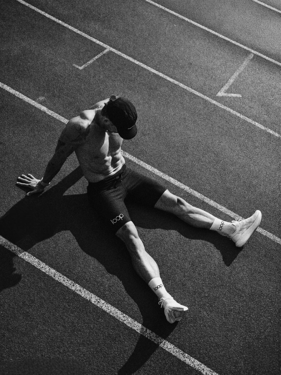 Athlete seated on a running track in Loop shorts and socks